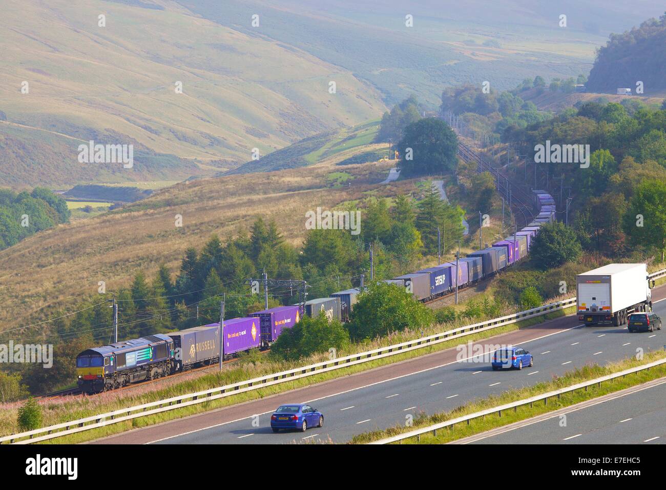 Direcr Rail Services (DRS) Diesel-Güterzug vorbei an der Autobahn M6 im Tal Flusses Lune. Howgills, Cumbria, Westküste Stockfoto