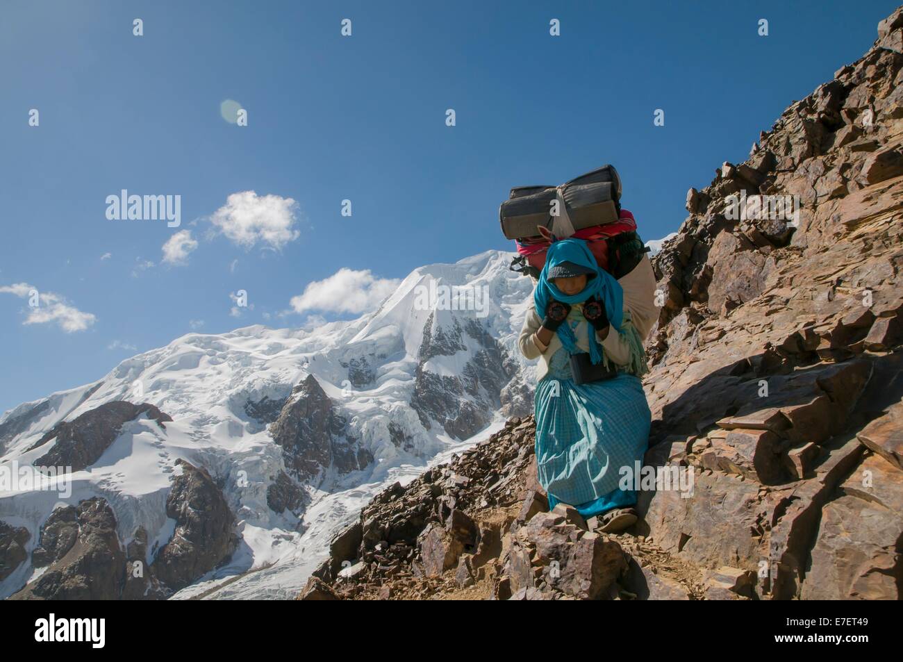 Ein Aymara Frauen Träger tragen Lasten der Kletterausrüstung bei 16.000 ft am Illimani ein 20.000 ft Peak in den bolivianischen Anden. Stockfoto