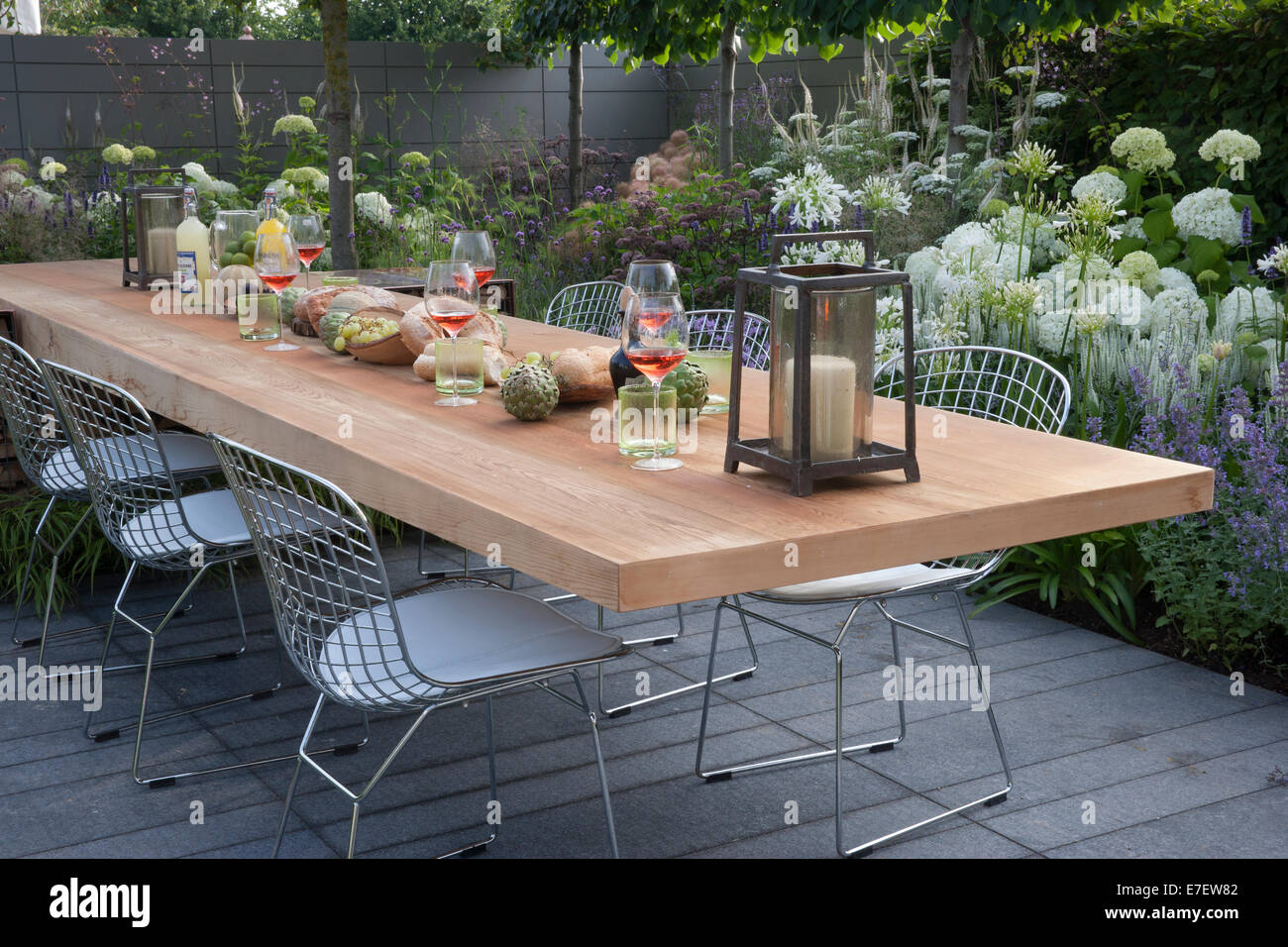 Gartenblick auf die Terrasse mit Gartenmöbeln, Tisch und Stühlen im Freien Wohnen Blumenränder Hydrangea Hydrangeas UK Hampton Court Flower Show Stockfoto