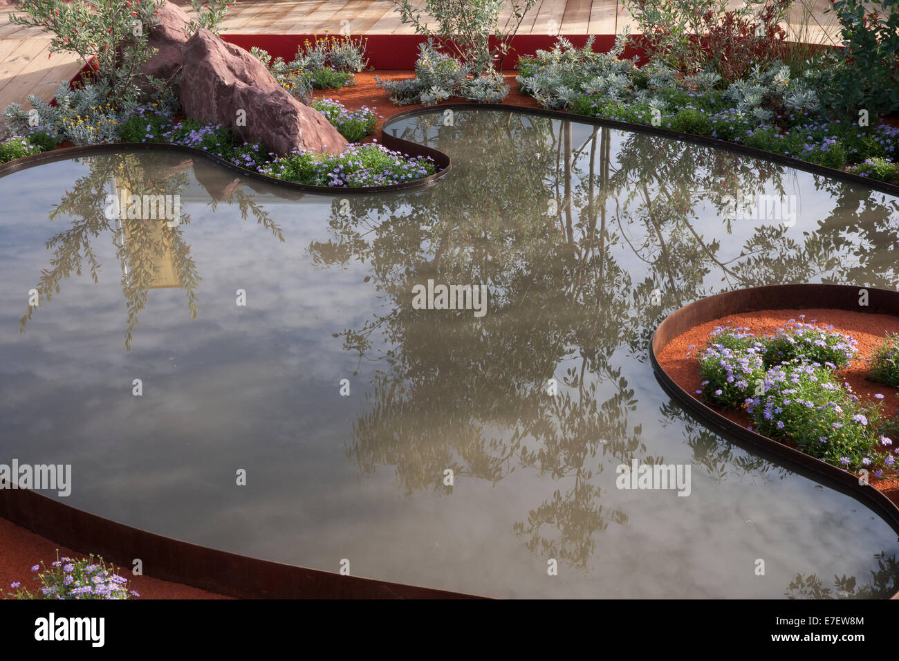 Blick auf den Garten - Essenz von Australien - Gartenteich Pool umgeben von Brachyscome blau - Designer - Jim Fogart Stockfoto