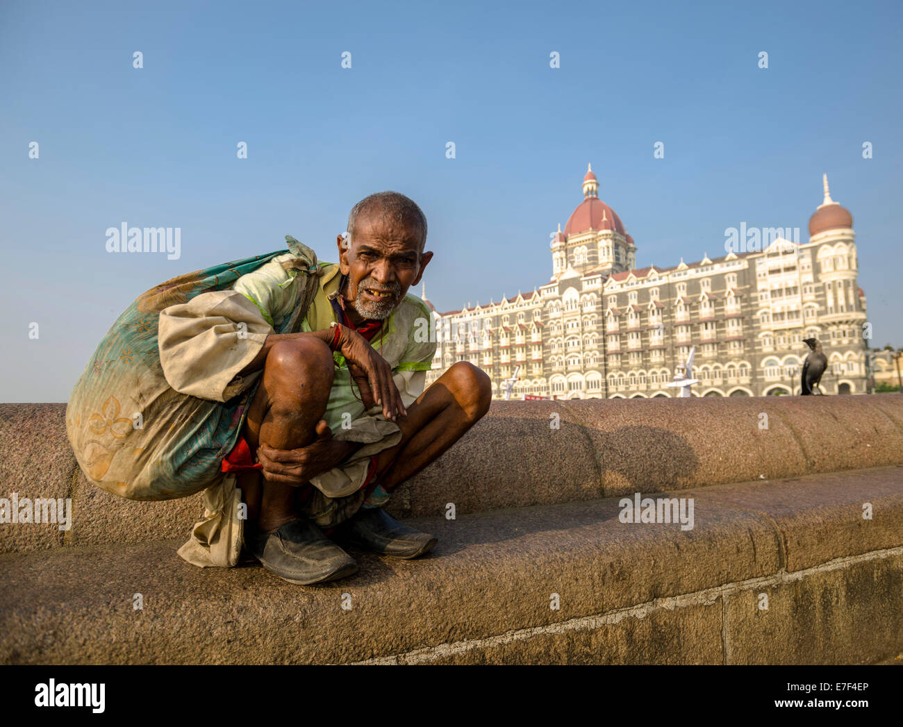 Ein Bettler sitzt vor der luxuriösen Taj Mahal Palace Hotel im Stadtteil Colaba, Mumbai, Maharashtra, Indien Stockfoto