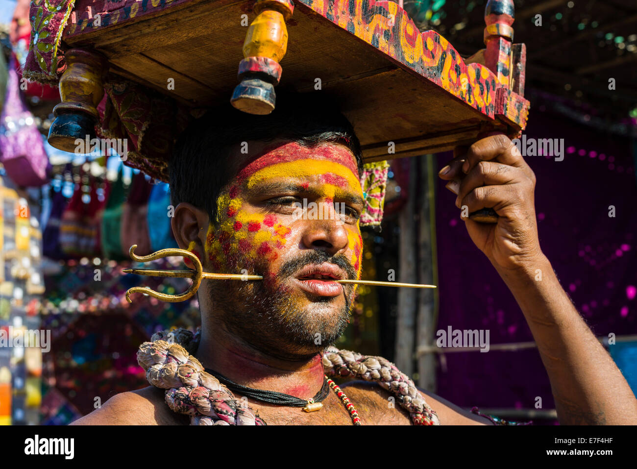 Ein Mann mit einem kleinen Messing-Dreizack durchbohrt seine Wange sammelt Geld für religiöse Zwecke auf dem wöchentlichen Flohmarkt Stockfoto