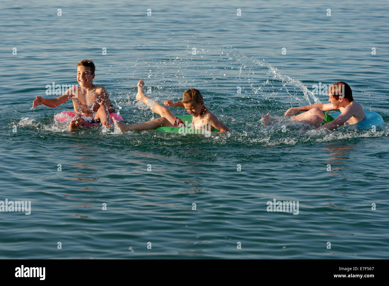 Wasser kämpfen, Kinder spielen auf schwimmenden Reifen im Meer, Mittelmeer, in der Nähe von Fano, Marken, Adria, Italien Stockfoto