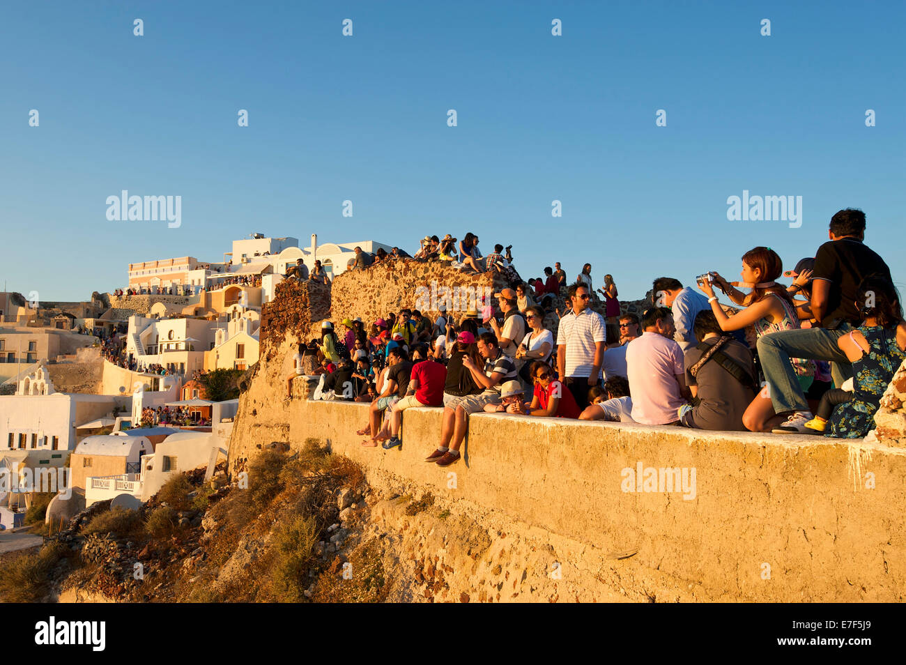Touristen, die Blick auf den Sonnenuntergang in Oia, Santorini, Kykladen, Griechenland Stockfoto