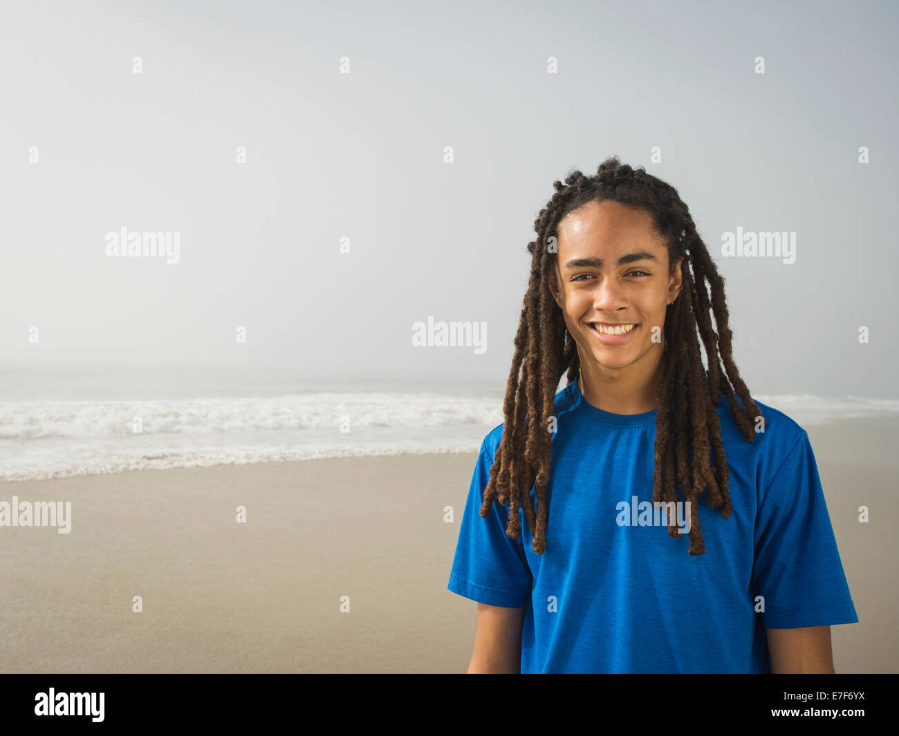 Schwarzer Teenager lächelnd am Strand Stockfoto