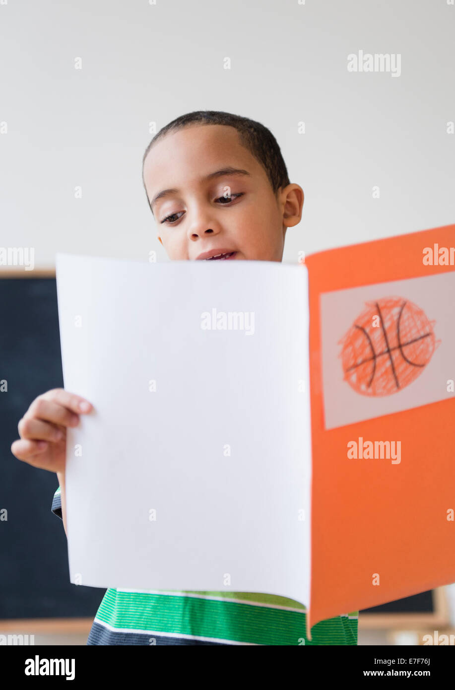 Gemischte Rassen Junge liest Bericht über Basketball in der Klasse Stockfoto