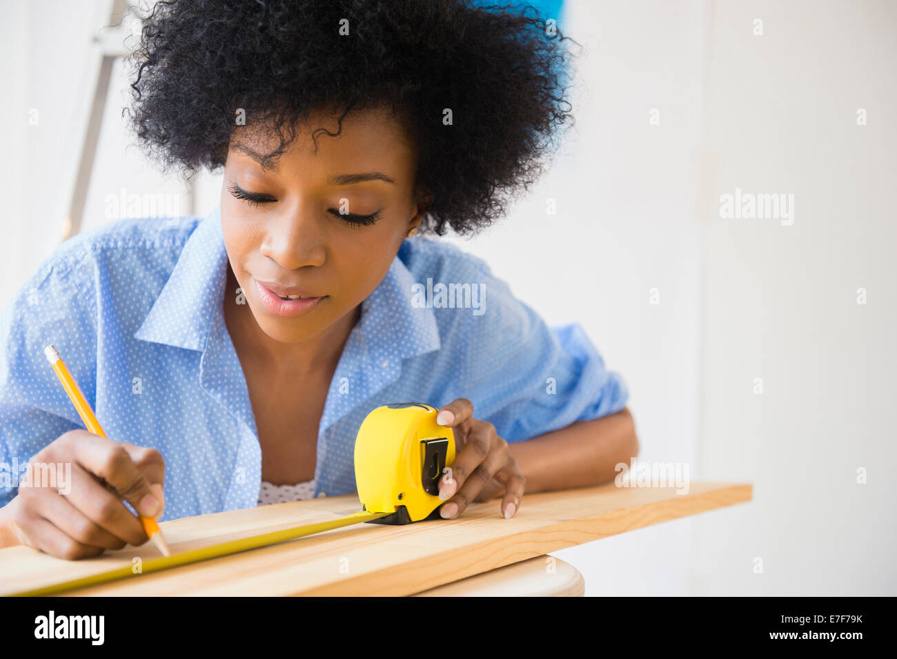 Afrikanische amerikanische Frau, die Messung von Holz Stockfoto