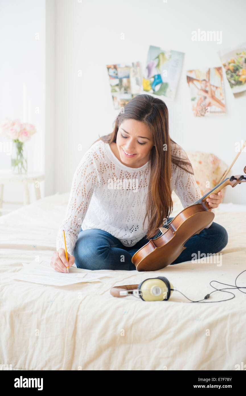 Frau spielt Violine und Notizen auf Bett Stockfoto