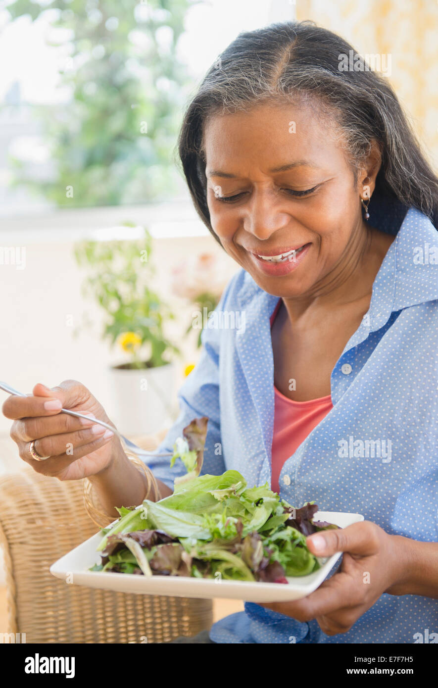 Gemischte Rassen Frau essen Salat auf sofa Stockfoto