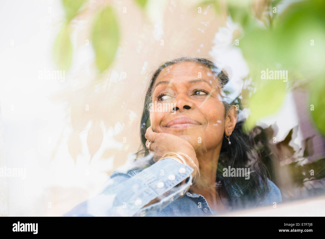 Gemischte Rassen Frau schaut aus Fenster Stockfoto