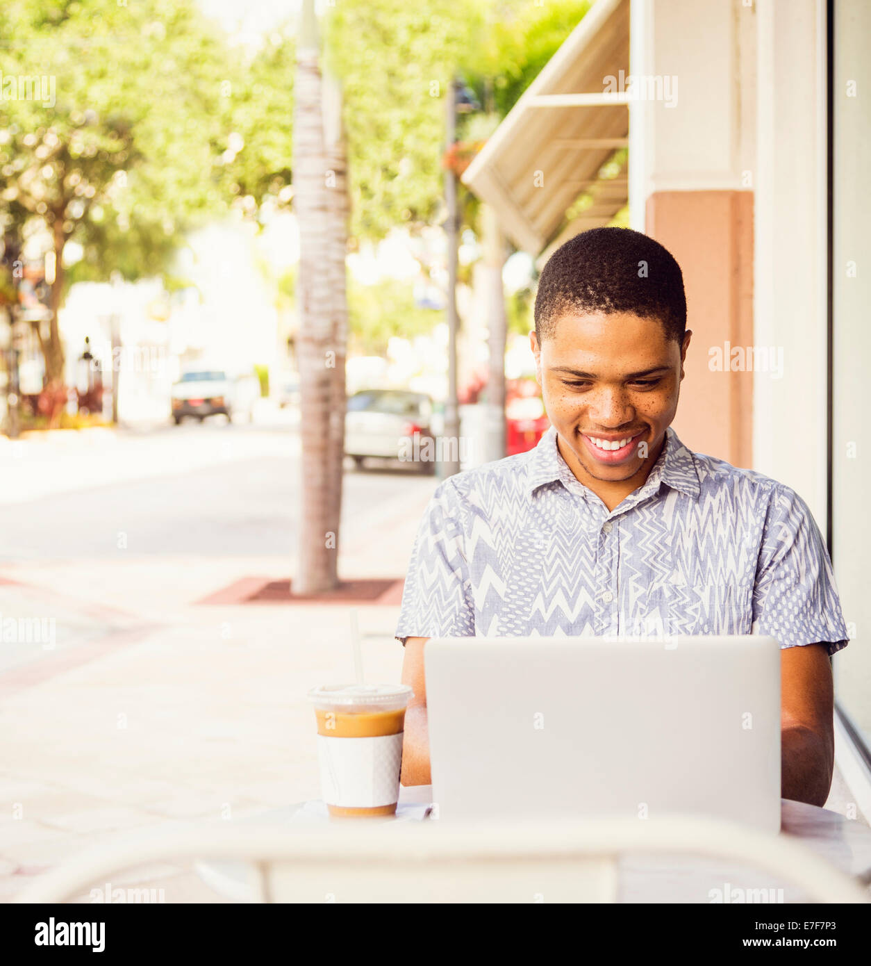 Afrikanische amerikanische Mann mit Laptop im Straßencafé Stockfoto
