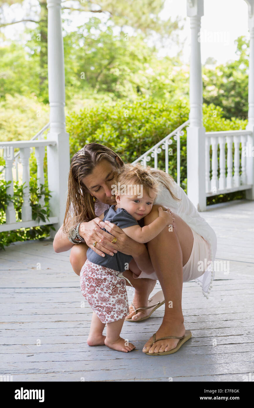 Kaukasische Mutter umarmt Kleinkind auf Veranda Stockfoto