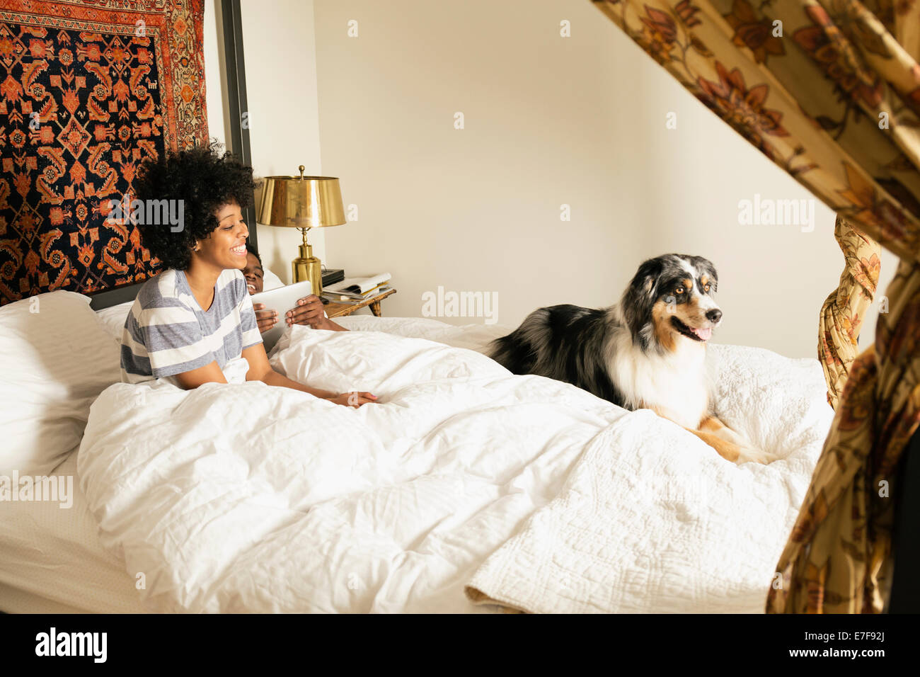 Gemischte Rassen Frau sitzt mit Hund im Bett Stockfoto