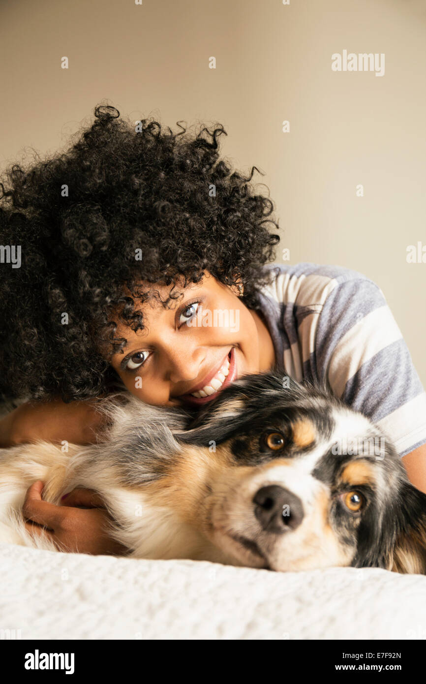 Gemischte Rassen Frau Verlegung mit Hund im Bett Stockfoto