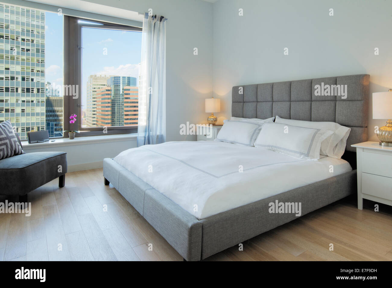 Bett und Sessel im Schlafzimmer mit Blick auf Stadt Wolkenkratzer Stockfoto