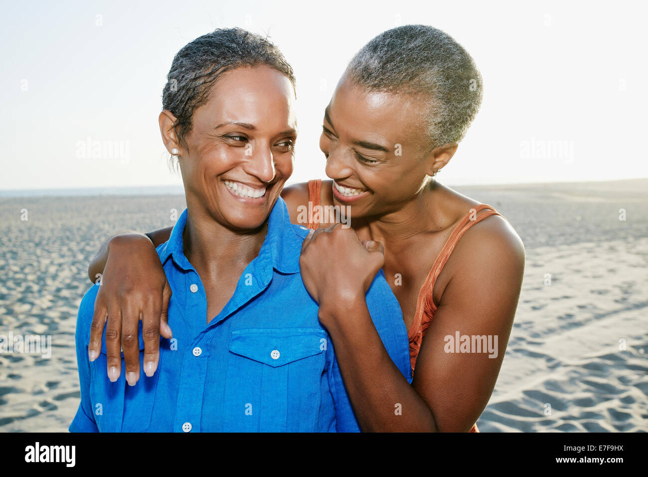 Ältere schwarze Frauen umarmen am Strand Stockfoto