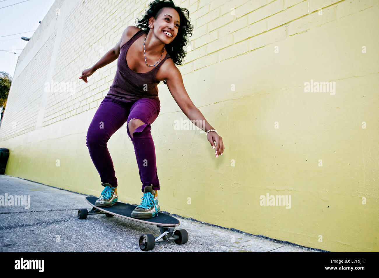 Hispanic Frau Reiten Skateboard auf Stadt Straße Stockfoto