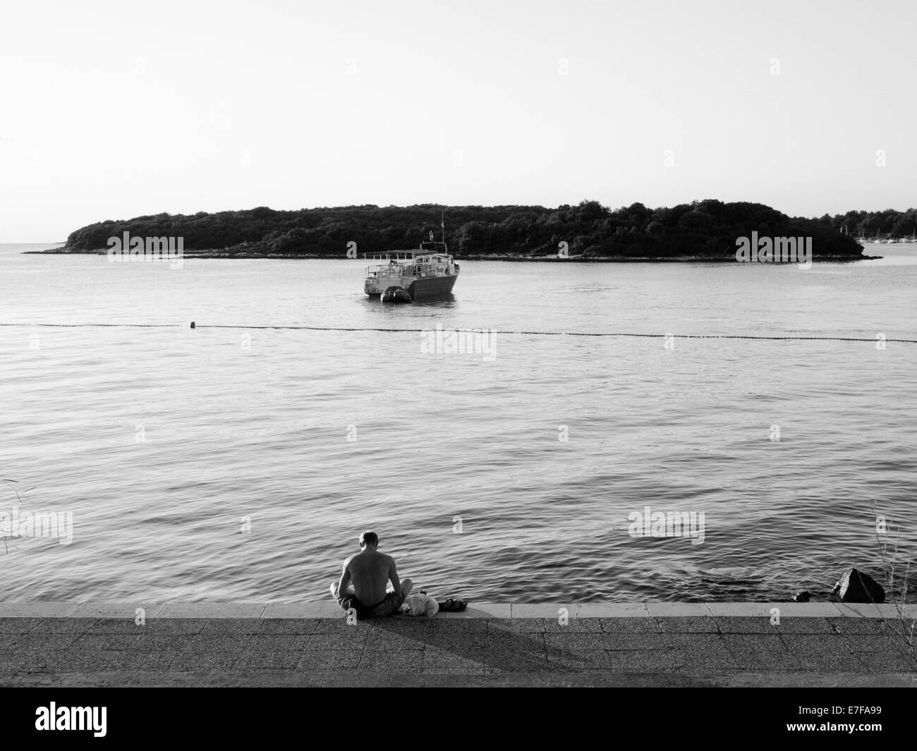 Muskulöser Mann auf der Anklagebank sitzen gerade Boot zum Hafen kommen. Fotografiert in Vrsar, Kroatien. Stockfoto
