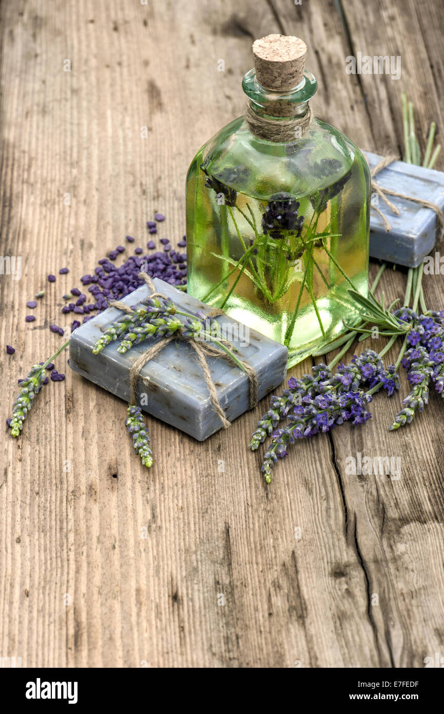 ätherisches Lavendelöl, Kräuterseife und Badesalz mit frischen Blumen auf hölzernen Hintergrund. Retro-Stil getönten Bild Stockfoto