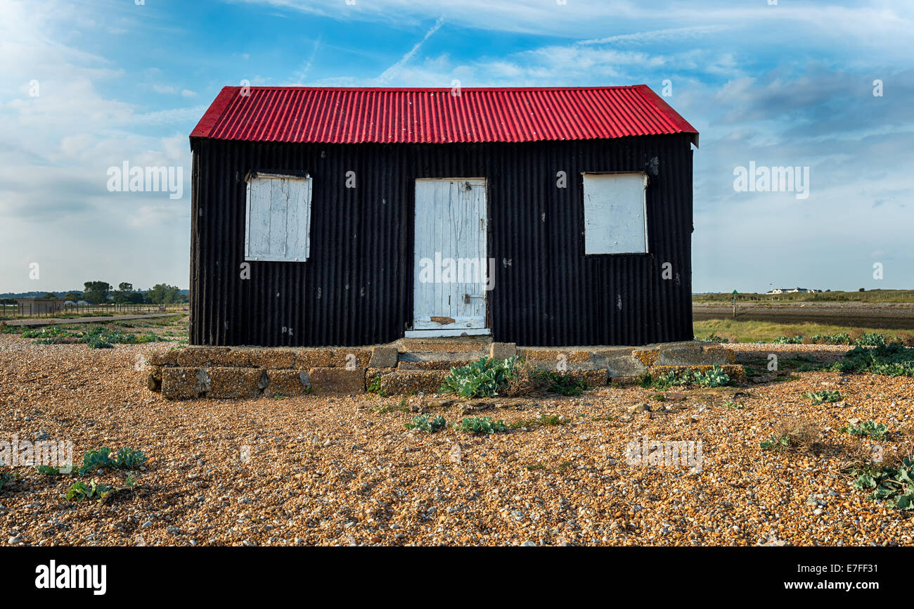 Einer alten Fischerhütte mit einem roten Blechdach am Ufer bei Roggen in East Sussex Stockfoto