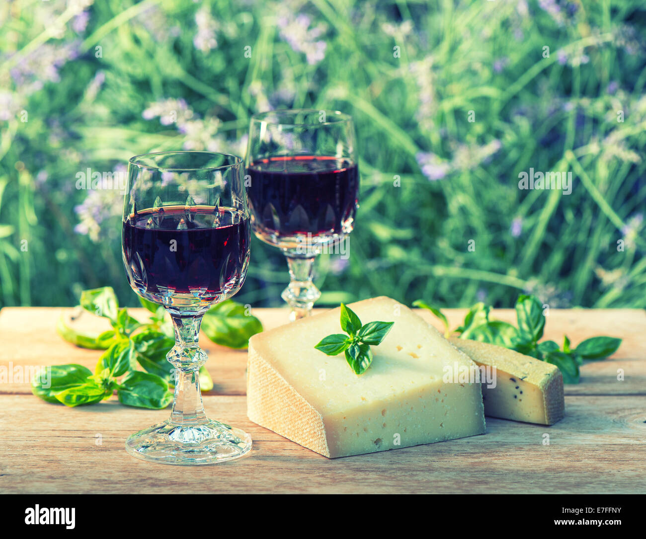 Käse mit Rotwein auf Holztisch im Freien. Retro-Stil getönten Bild Stockfoto