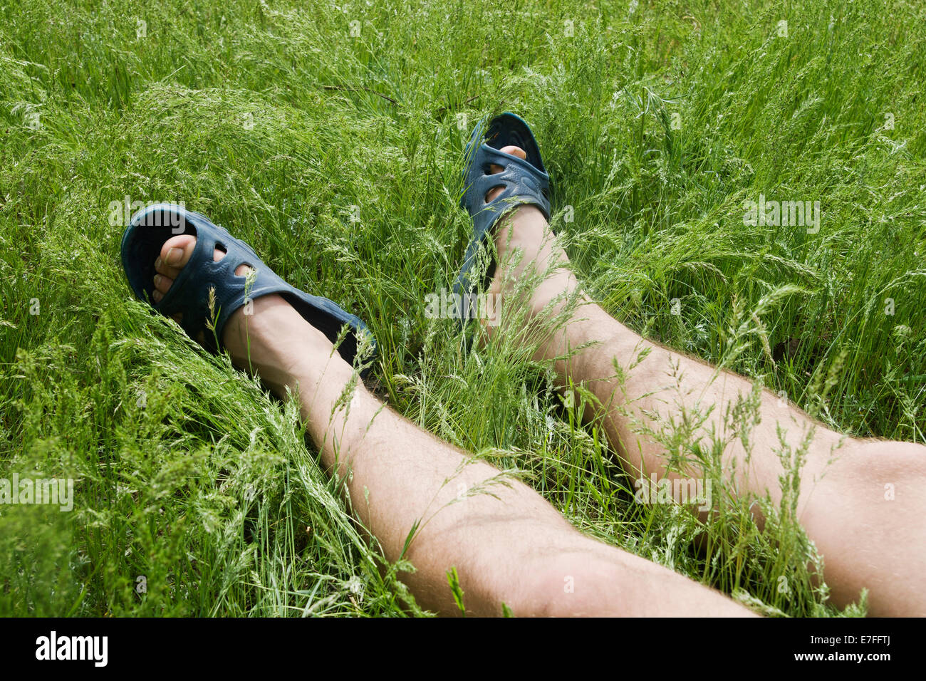 Beine eines Mannes legen in dem Rasen an einem sonnigen Tag Stockfoto