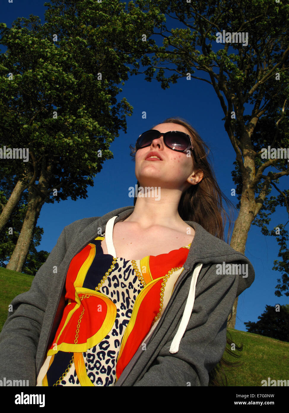 Teenager-Mädchen posiert in Sonnenschein gegen blauen Himmel Stockfoto