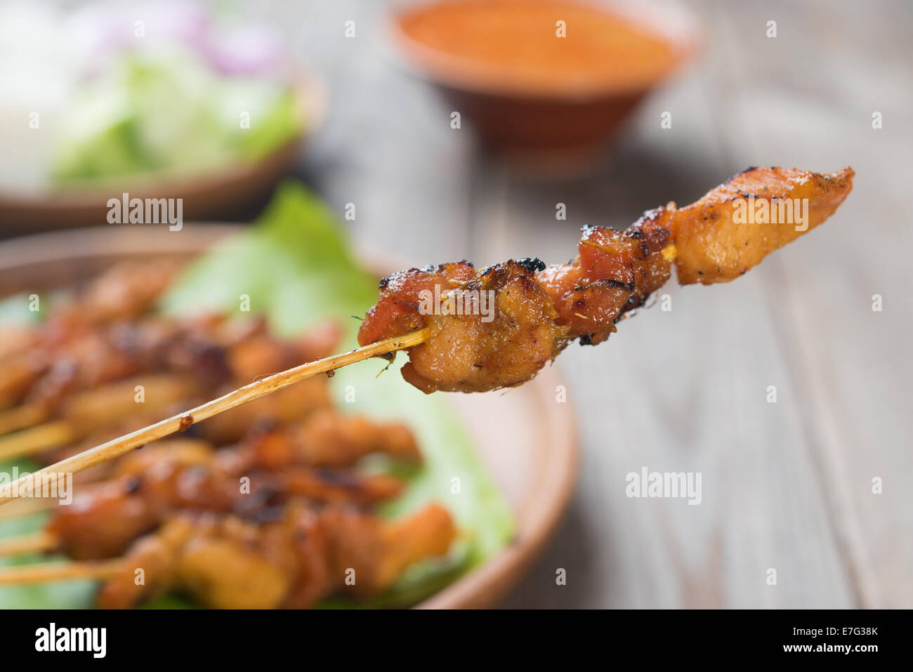Leckere Hähnchen-Satay am Esstisch aus Holz, eines berühmten lokalen Gerichte hautnah. Stockfoto