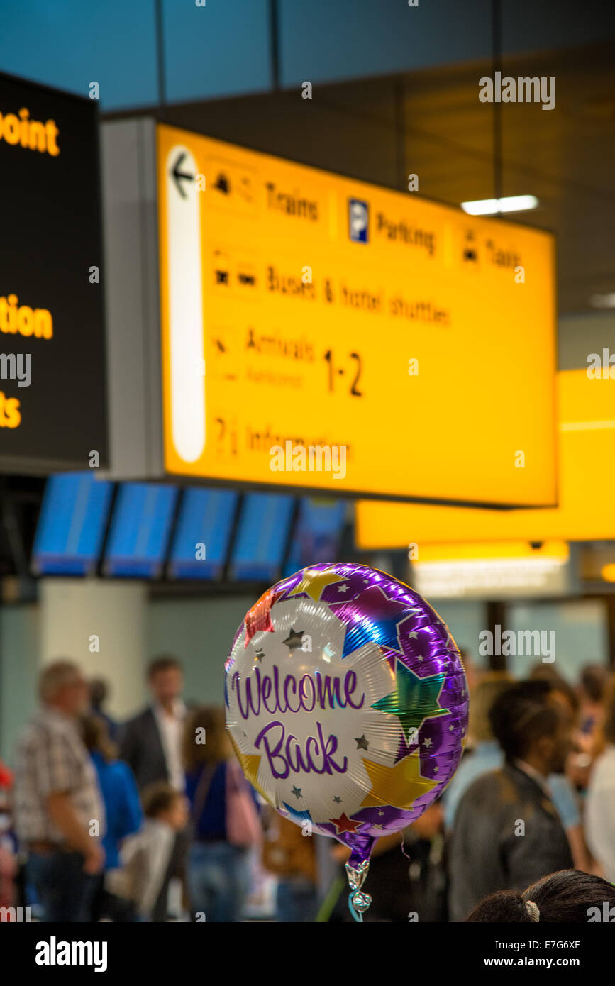 Menschen mit willkommen Ballon am Schiphol Flughafen in der Ankunftshalle warten Stockfoto