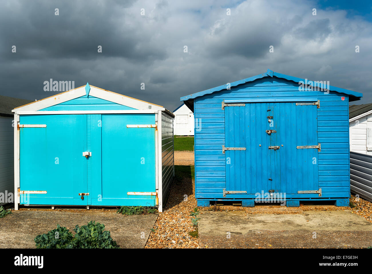 Blaue Strandhütten unter einem dramatischen Himmel am St Leonards on Sea in Hastings, East Sussex Stockfoto