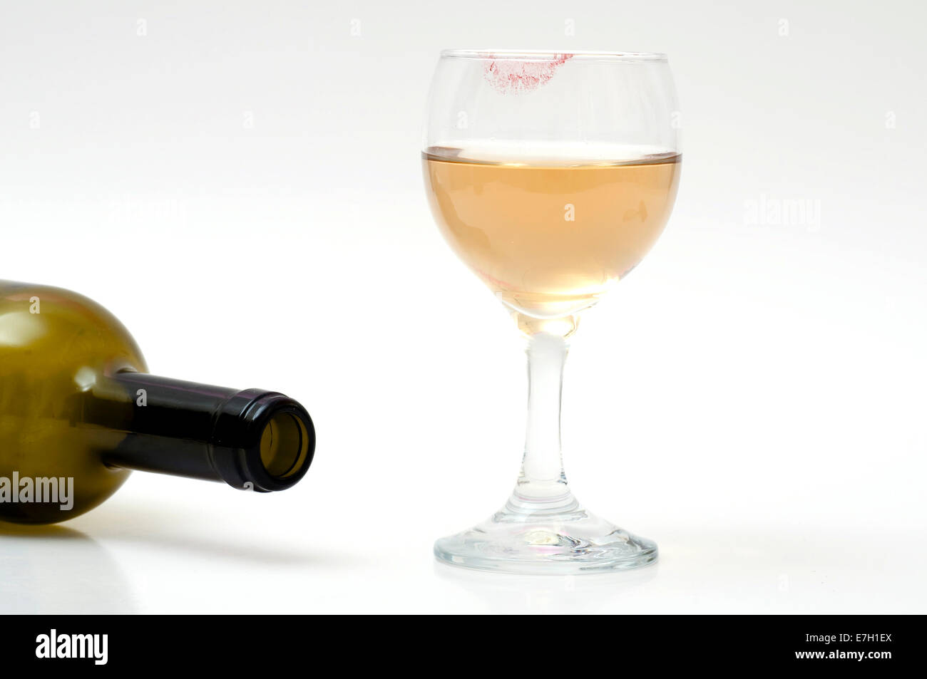 Leere Flasche Wein und ein Glas Wein mit Lippenstift am Glas. Stockfoto