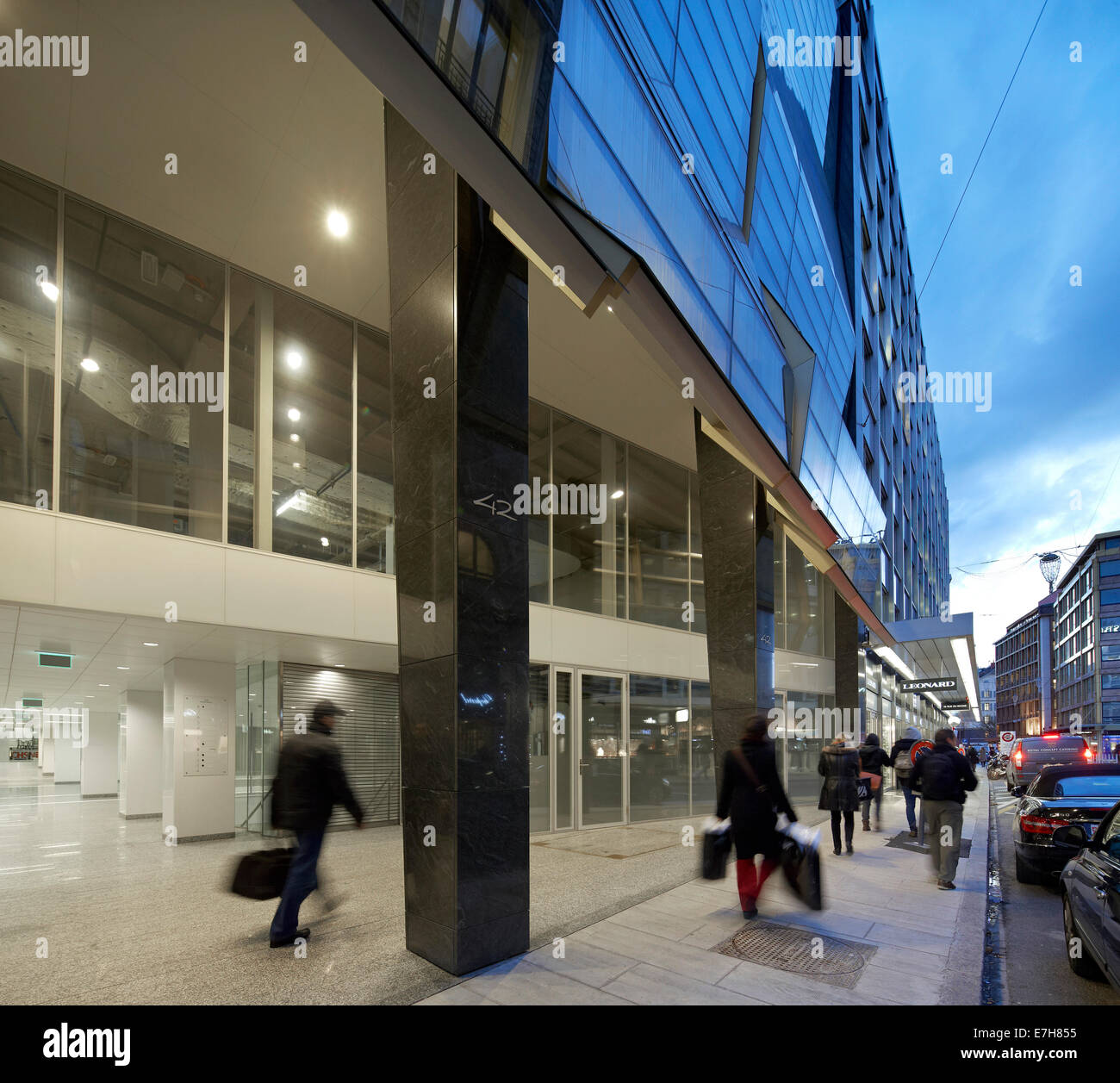 42 rue du Rhône in Genf, Schweiz. Architekt: Sheppard Robson, 2012. Abenddämmerung Blick auf Eingang im Erdgeschoss und Straße. Stockfoto