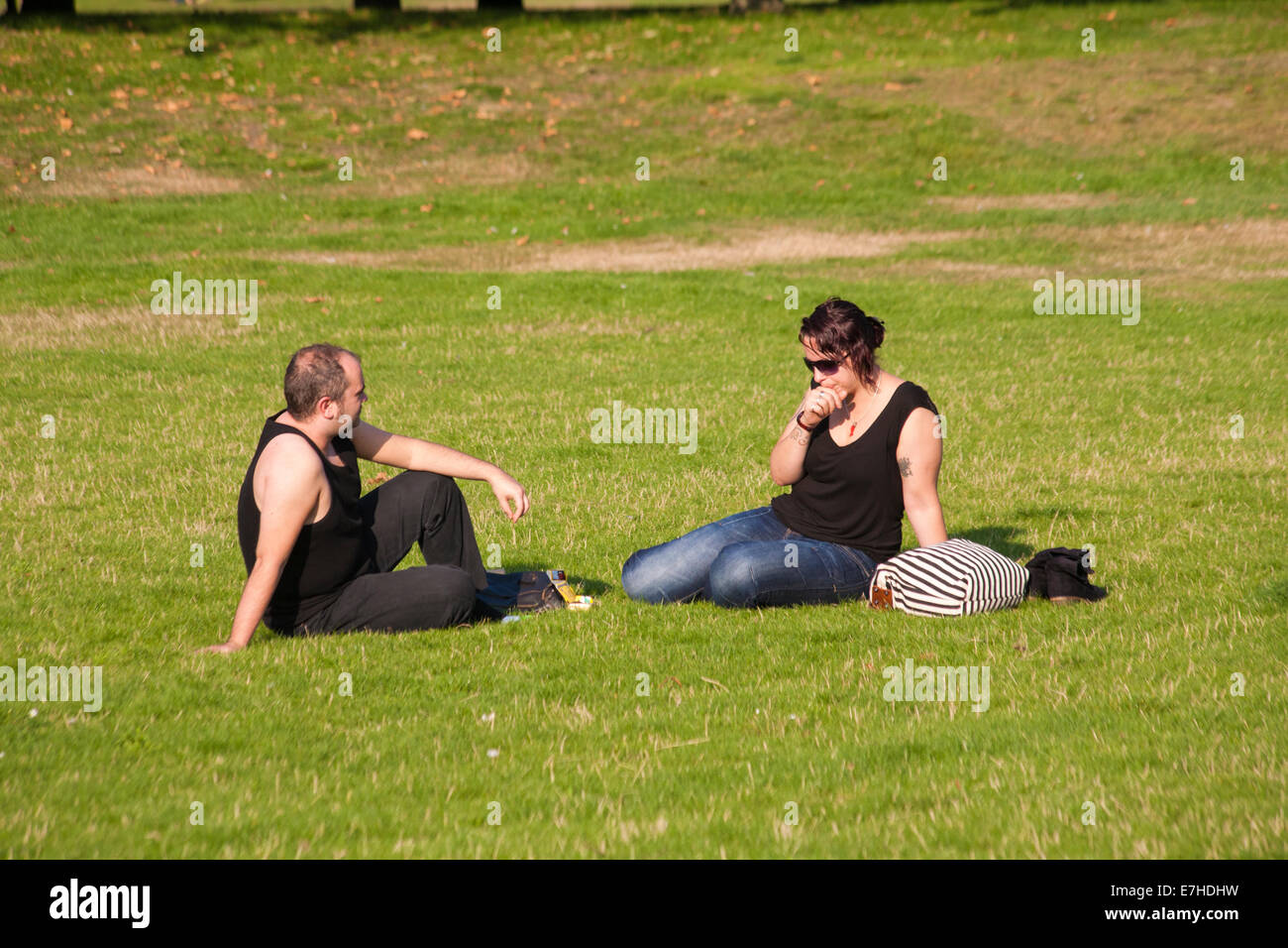 Paar, sitzen auf dem Rasen in Greenwich, London im September Stockfoto