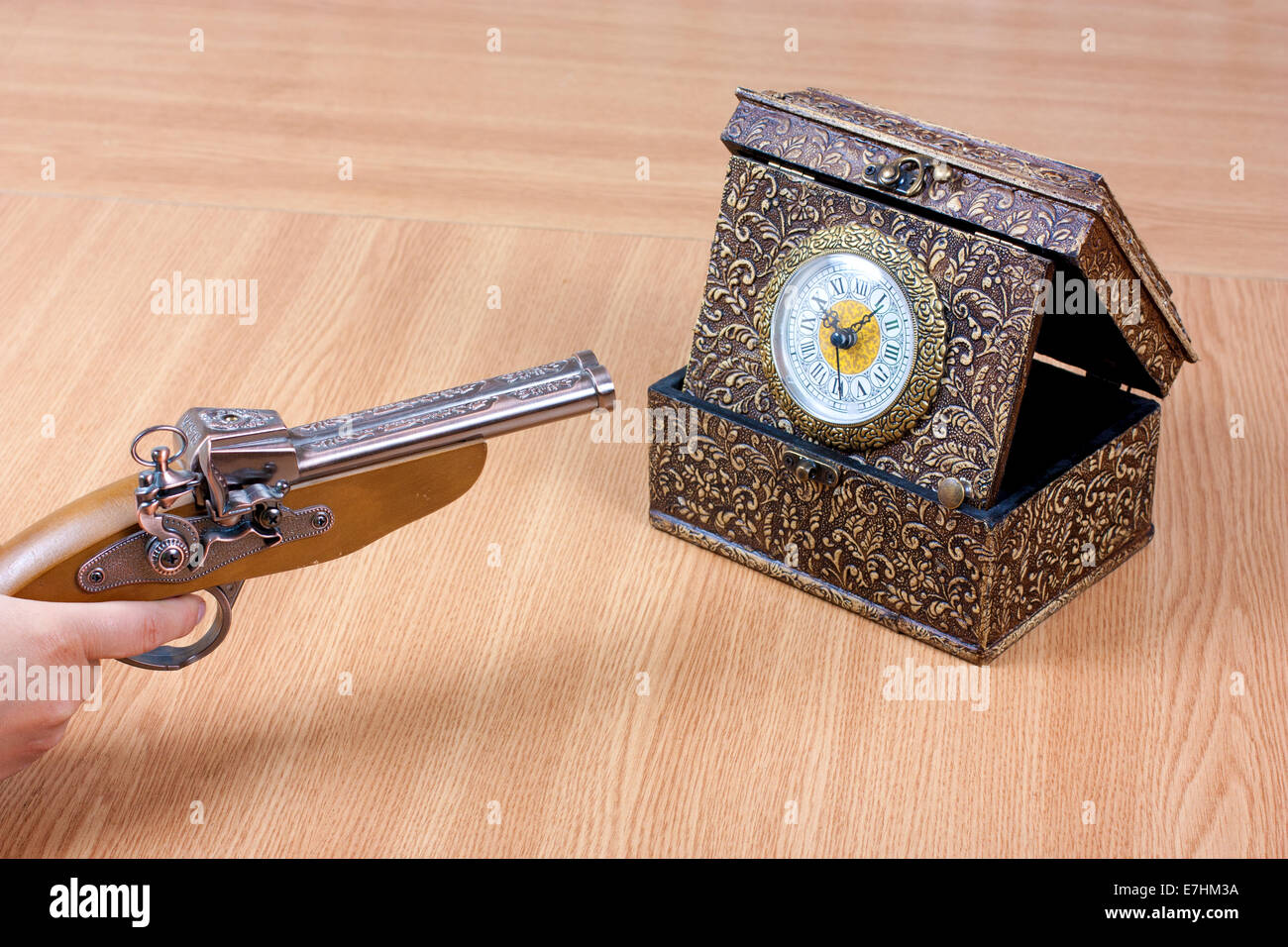 Alte Uhr mit einer Person mit einer Pistole auf sie. Betont durch die Zeit Stockfoto