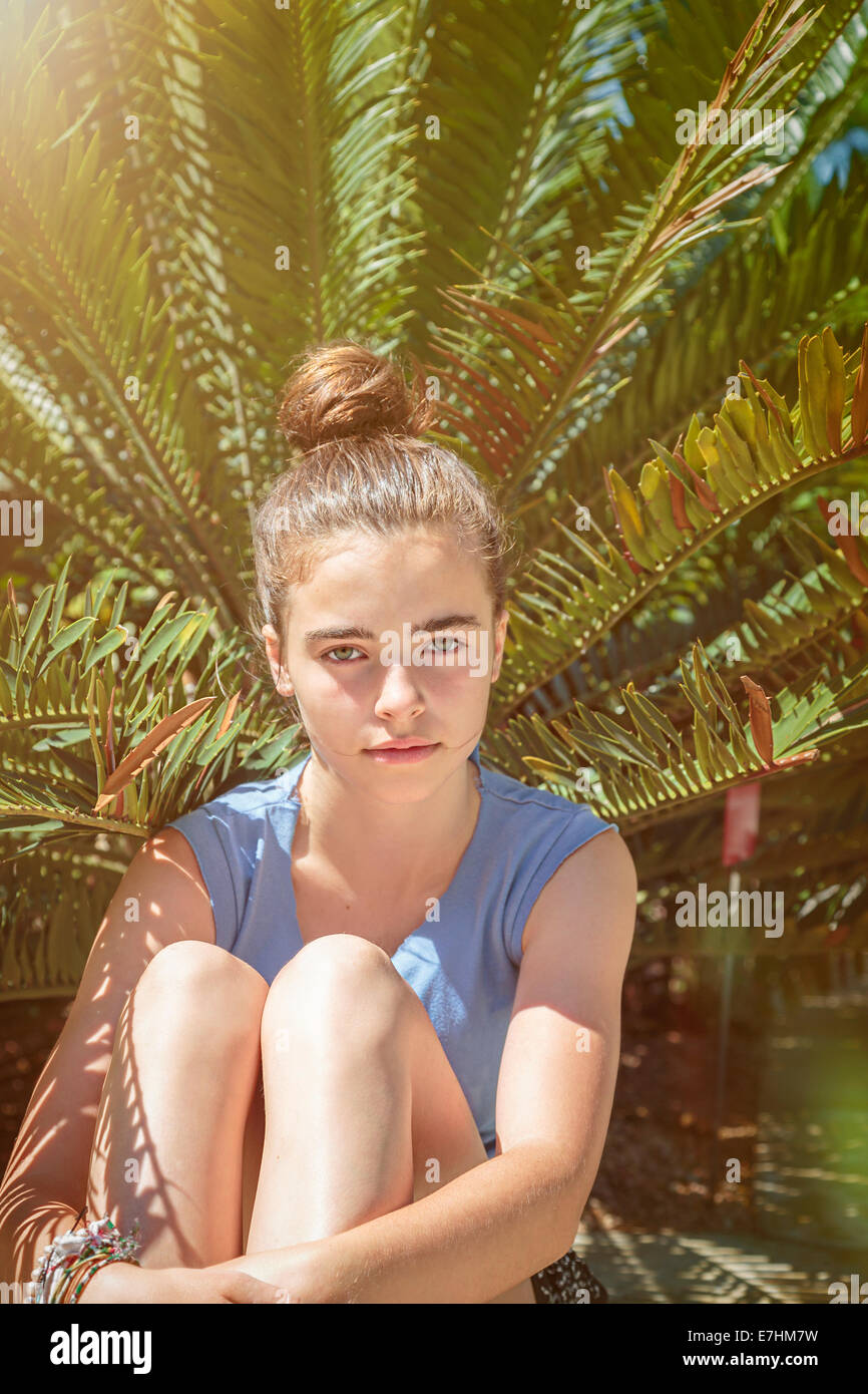 Porträt von einem Teenager-Mädchen, vor einer Palme sitzen Stockfoto
