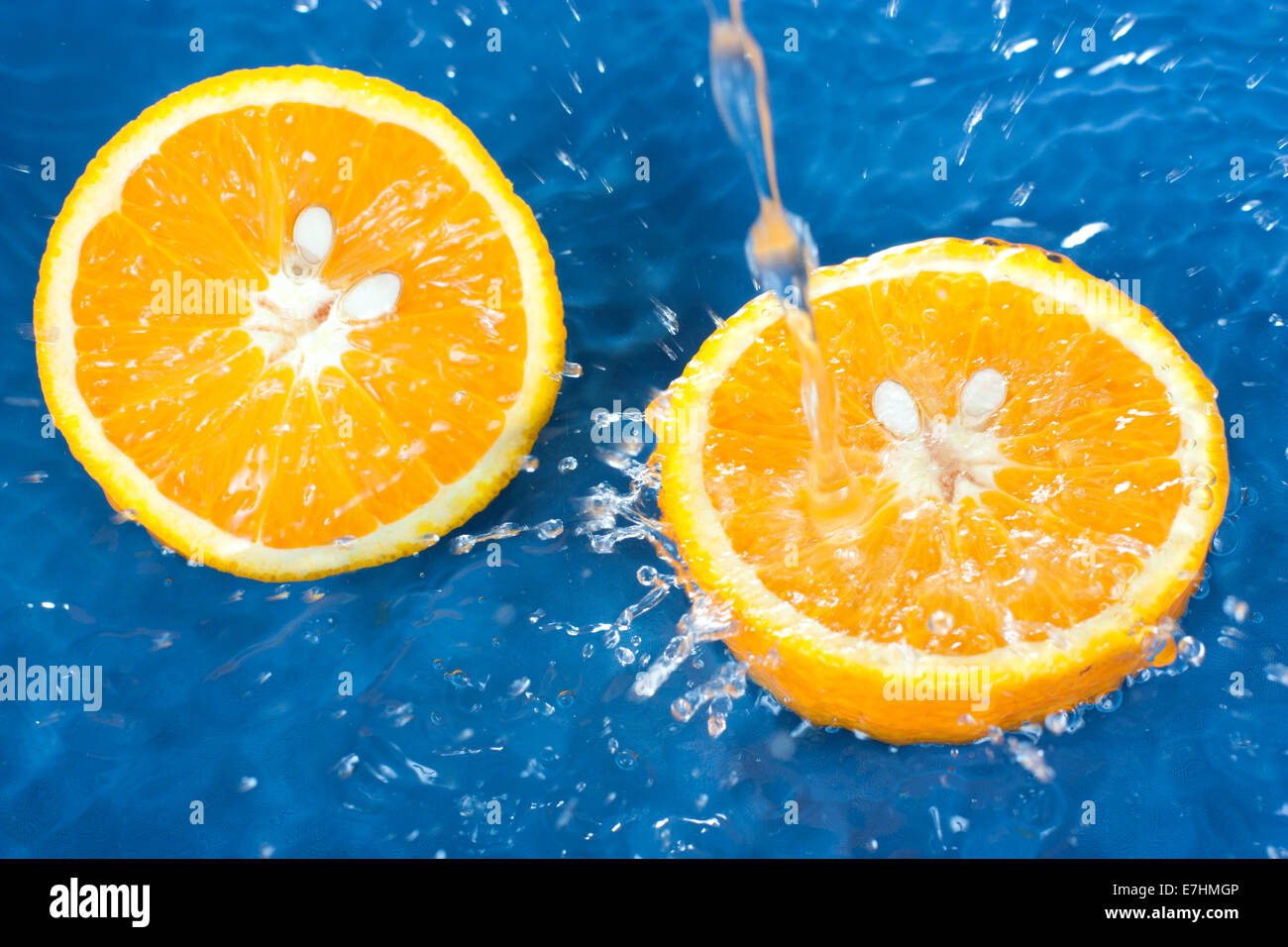 Frische Orange im strömenden Wasser auf blauem Hintergrund Stockfoto