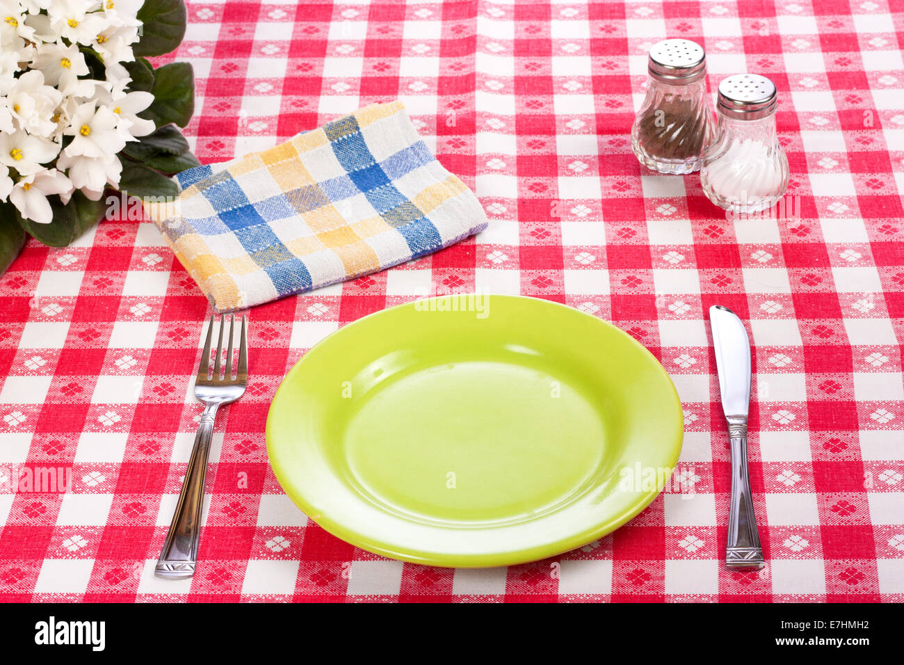 Messer, grüne Platte und Gabel auf roten aufgegebenes Tischdecke Stockfoto