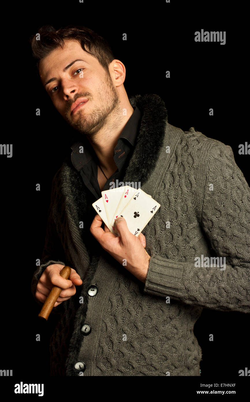Junger Mann, der Karten und rauchende Zigarre, auf schwarzem Hintergrund isoliert Stockfoto