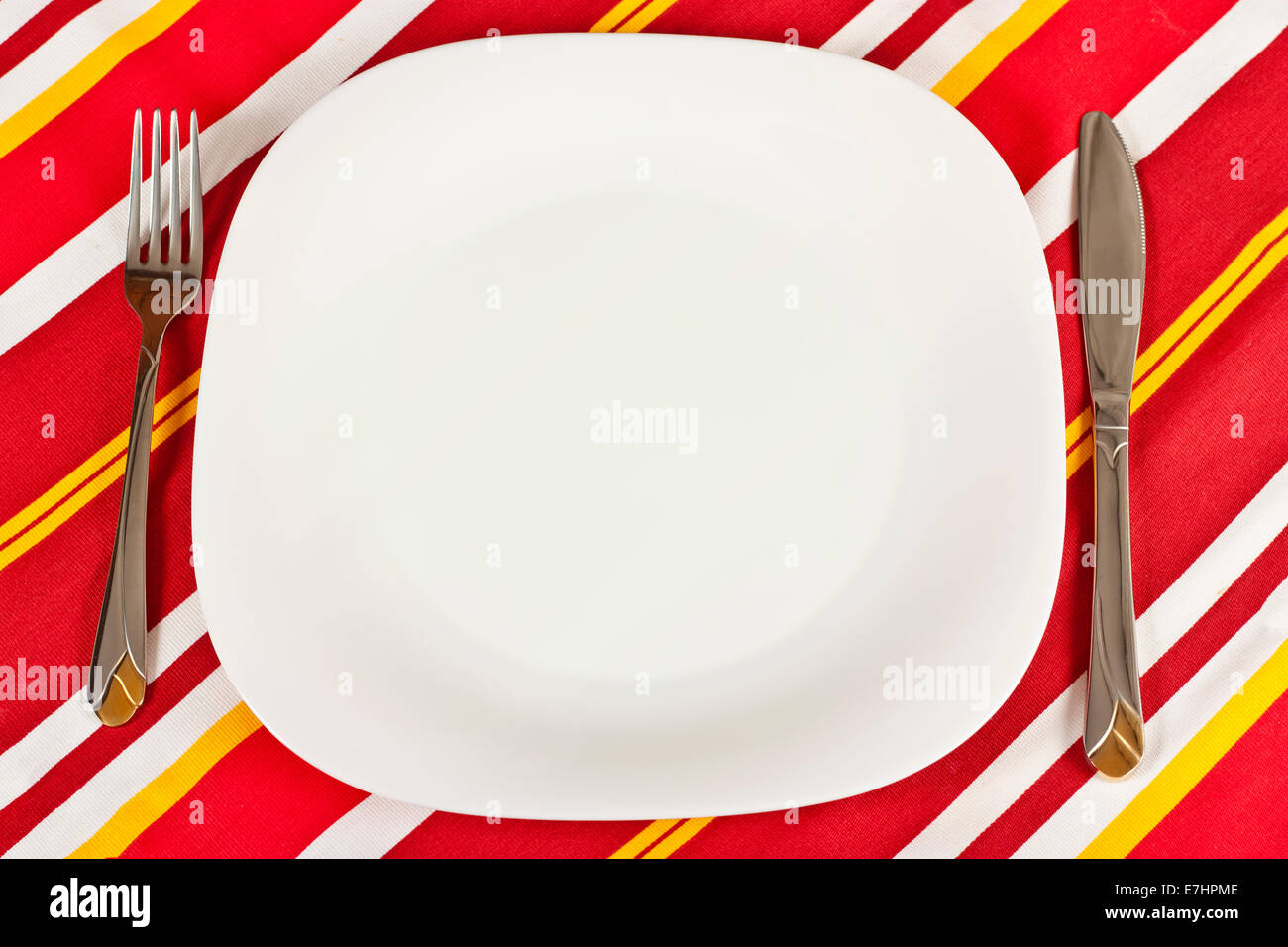 Messer, weißen Teller und Gabel auf roten aufgegebenes Tischdecke Stockfoto
