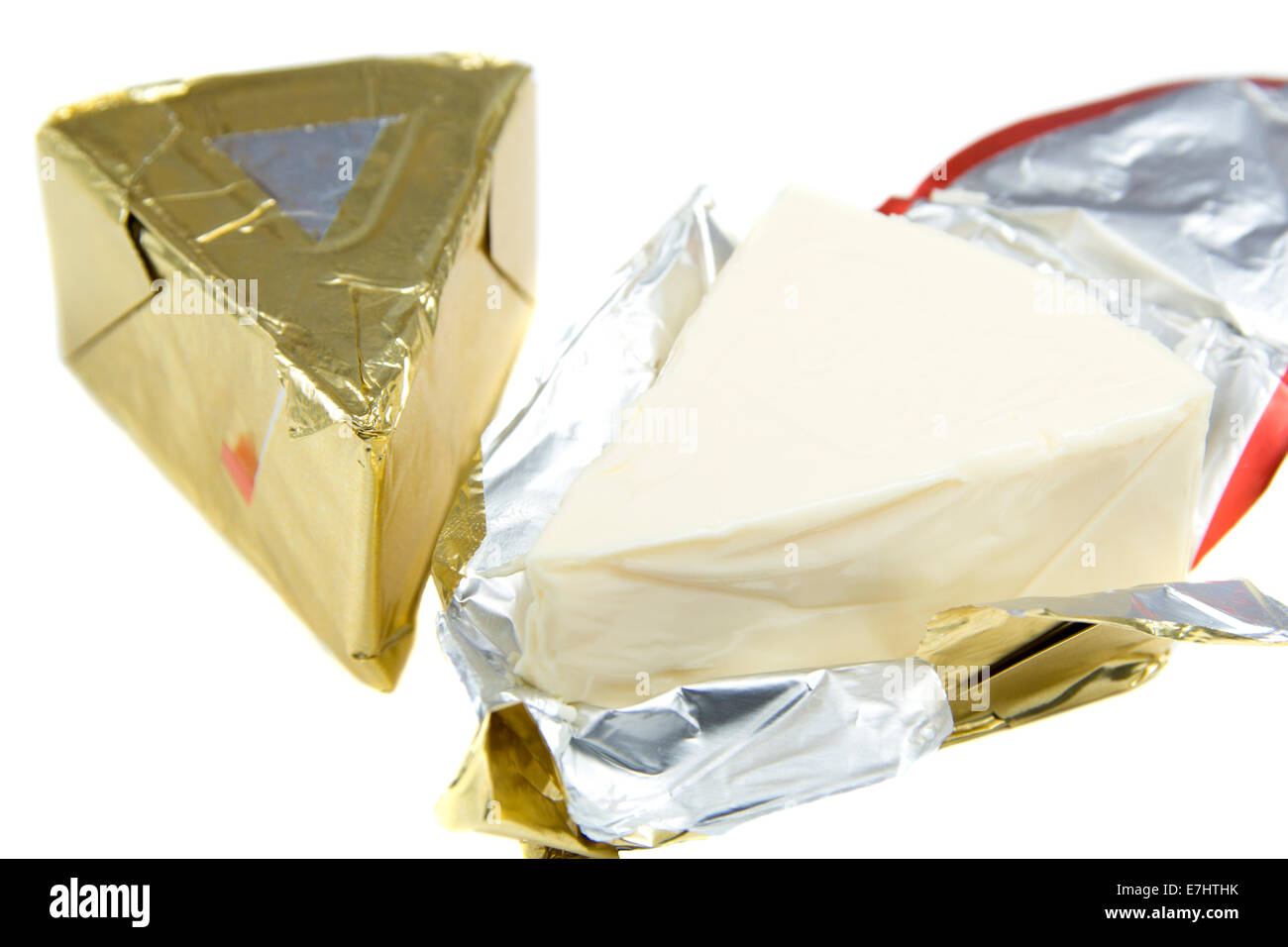 Dreieck Stück Käse in Goldfolie auf weißem Hintergrund Stockfoto