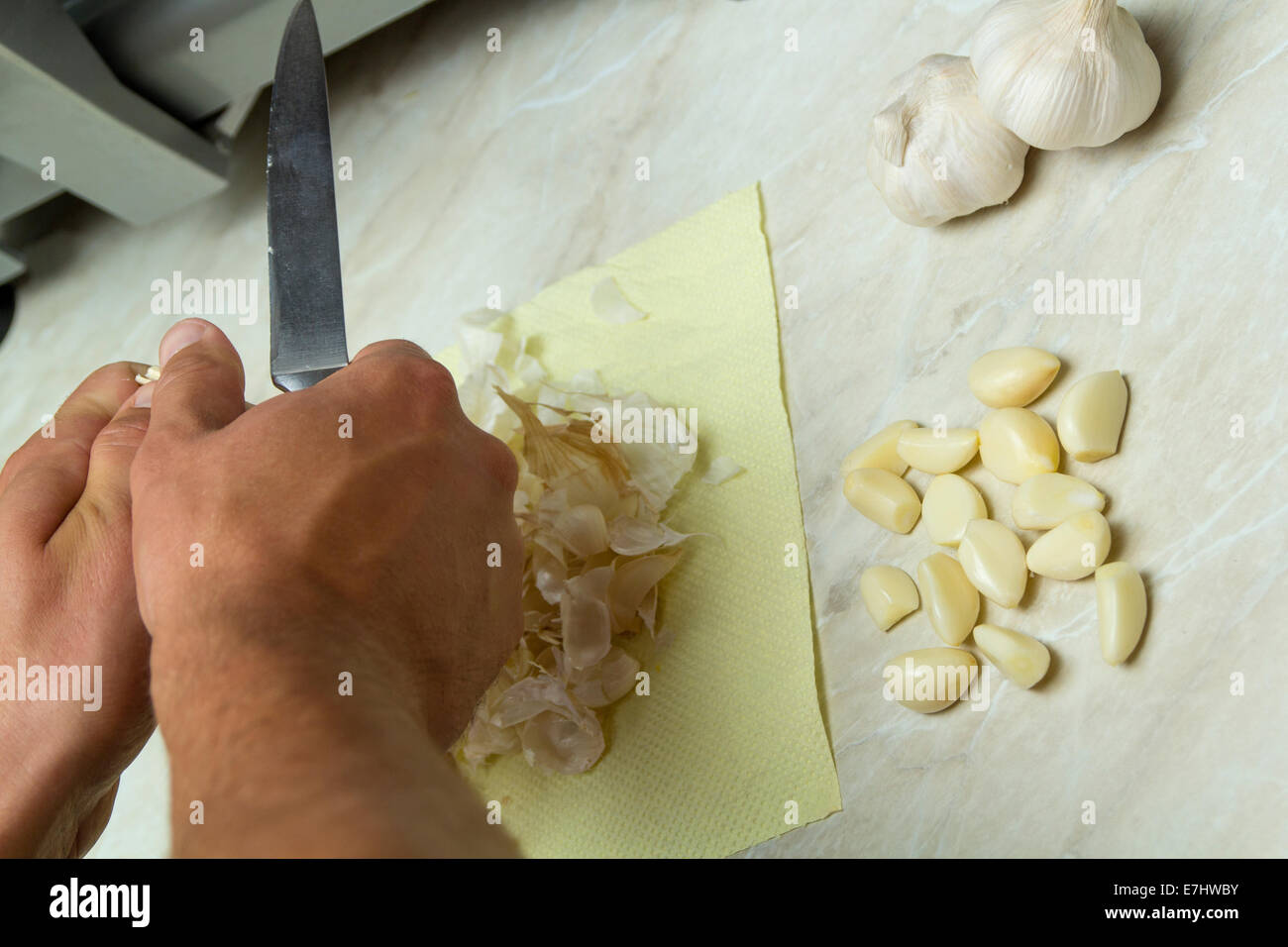 Männlichen Chef schneidet Knoblauch mit einem Küchenmesser auf Tisch Stockfoto