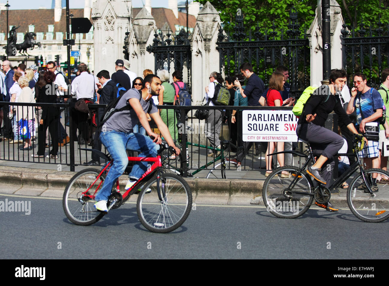 Zwei Radfahrer unterwegs um eine Kurve in Parliament Square, London. Menschen sind Fuß auf dem Bürgersteig. Stockfoto