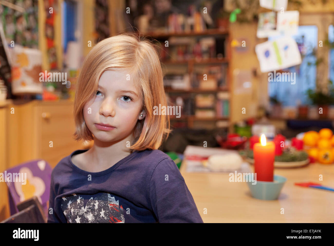 Trauriges Mädchen, 9, sitzen an einem Tisch mit einer Kerze Stockfoto