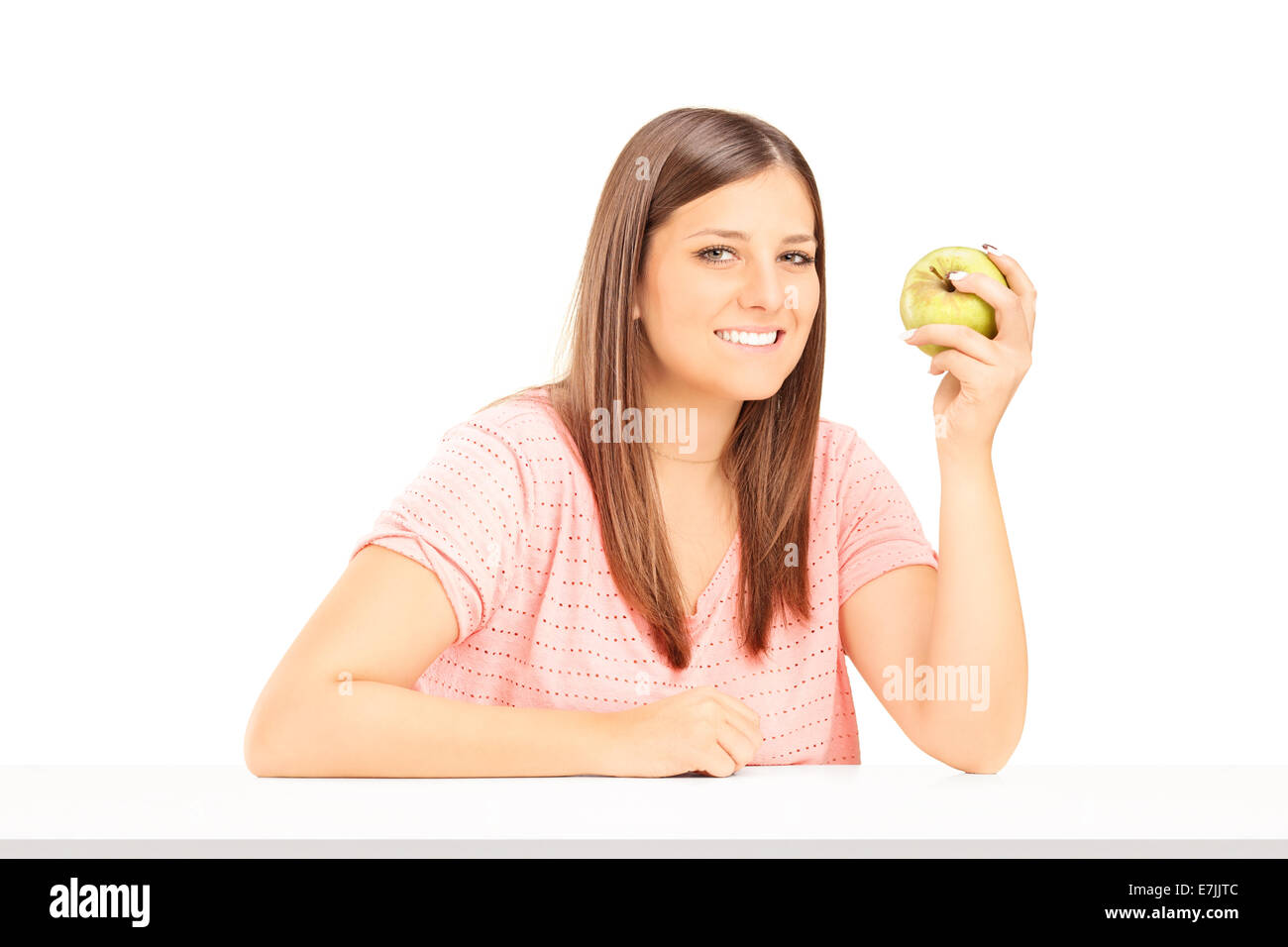 Junge Frau hält einen Apfel und am Tisch sitzen Stockfoto