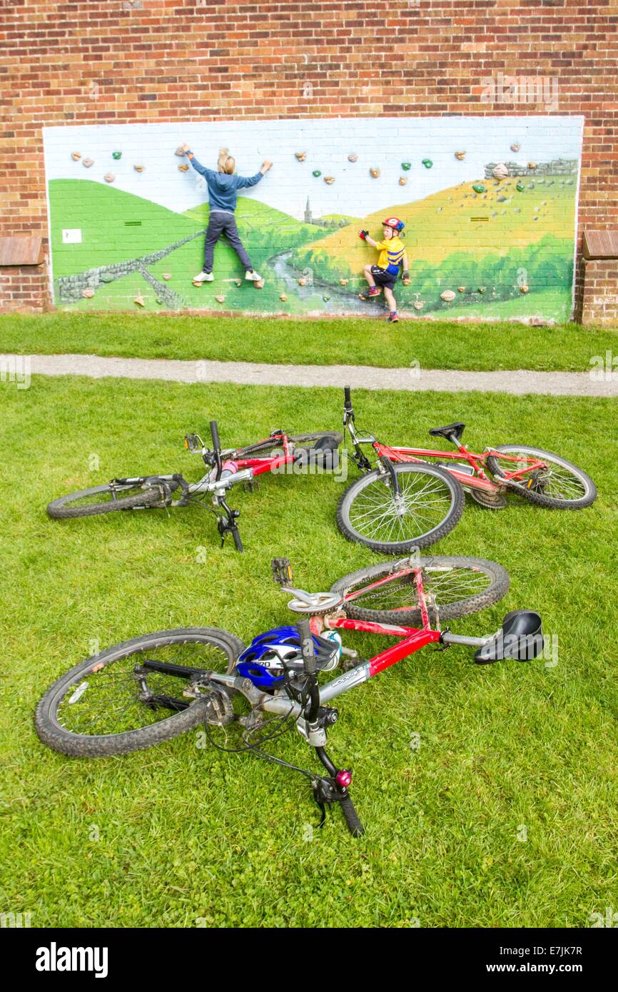 Kinder spielen an einer Kletterwand neben Zyklen auf dem Thornbridge im freien Bike Festival in großen Longstone nr Bakewell Stockfoto