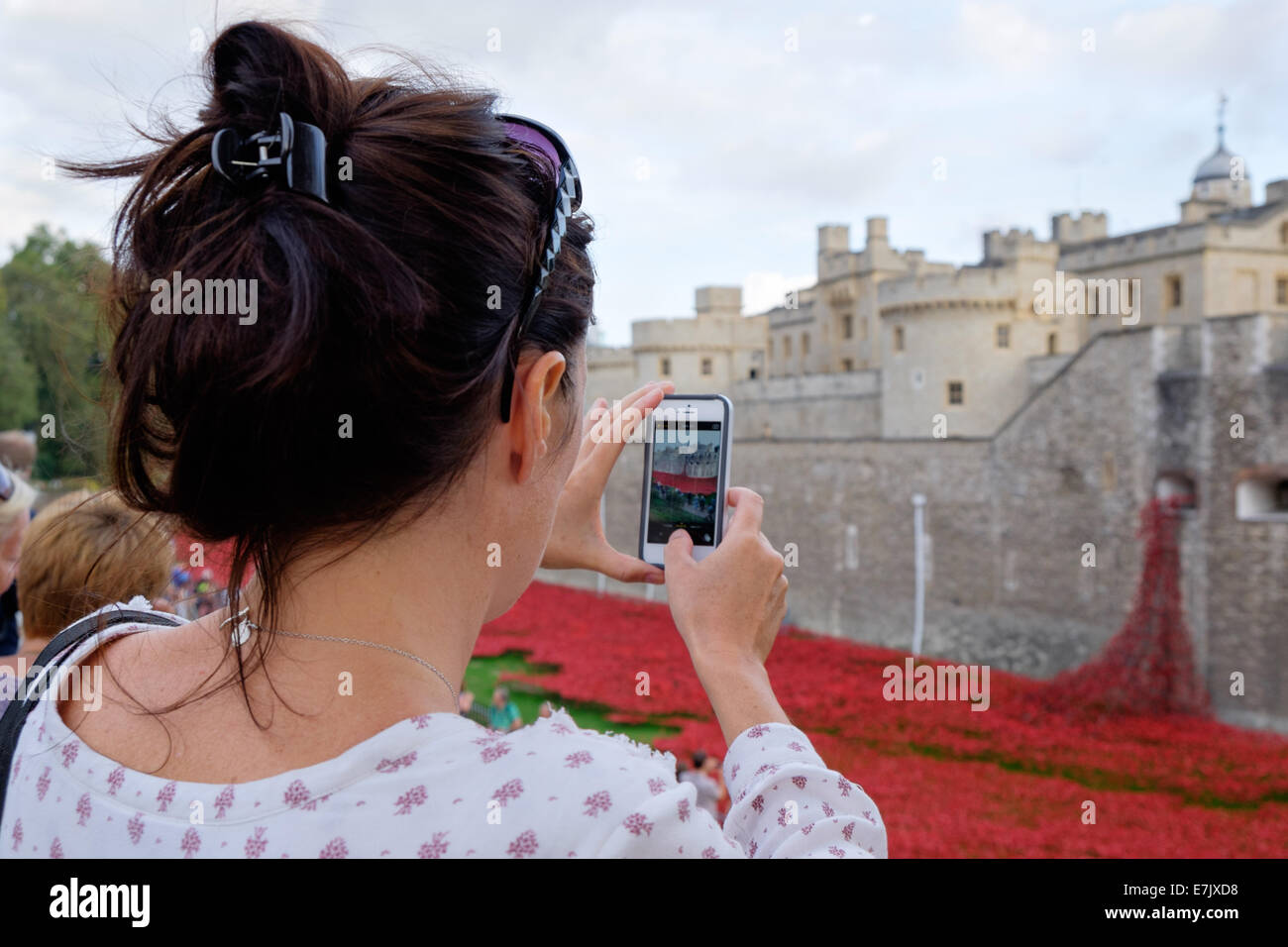 London Touristen Frau Aufnahme eines Fotos auf einem Iphone die Gedenkstätte Keramik Mohnblumen in den Tower of London, London, England. Stockfoto