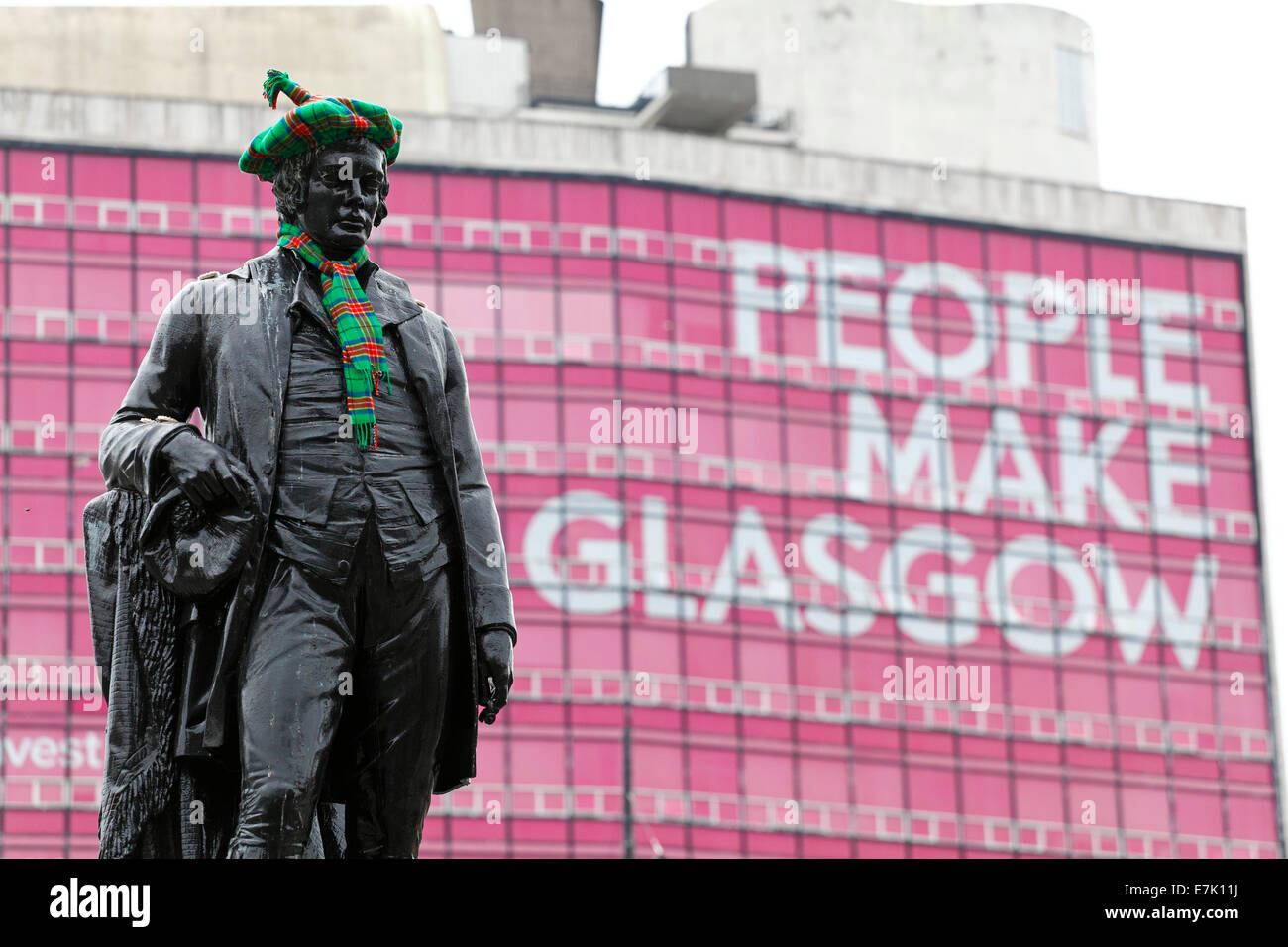 Eine Statue des schottischen Dichters Robert Burns mit einem Tartan Hut und Schal vor den Menschen gemacht Glasgow Zeichen, George Square, Glasgow, Schottland, Großbritannien Stockfoto