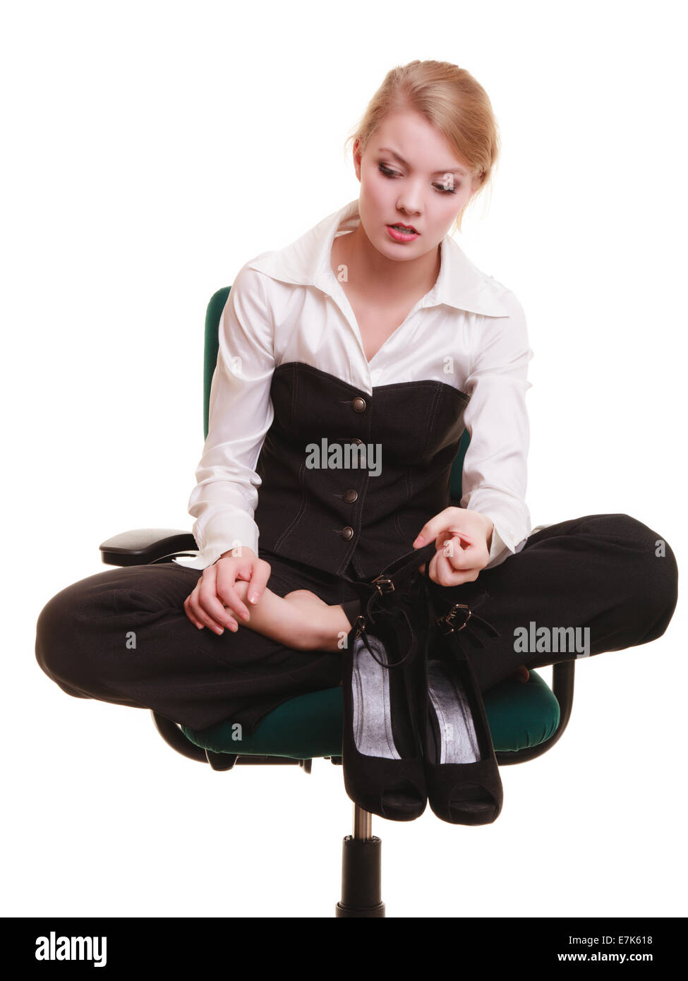 Pause von der Arbeit. Müde Geschäftsfrau mit Schmerzen in den Beinen. Junge Frau massiert ihre Füße auf Stuhl isoliert auf weiss. Stockfoto