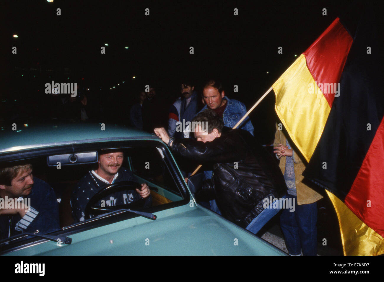 West Berlin, Deutschland. 23. Sep, 2009. Menschen, die eine deutsche Flagge  winken Grüße ein Auto es kreuzt die innerdeutsche Grenze in der Nähe von  Helmstedt, Deutschland am 9. November 1989. Die Grenzen