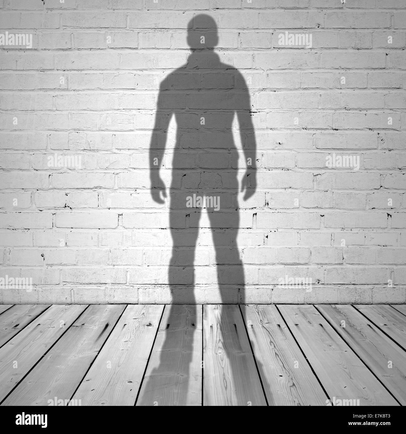 Schatten eines Mannes auf weißen Ziegelmauer und Holzboden Stockfoto